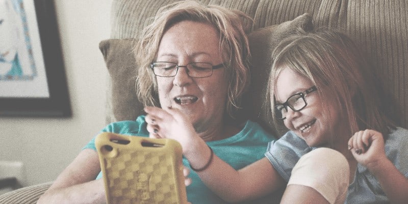 Grandmother and granddaughter smiling at smartphone together